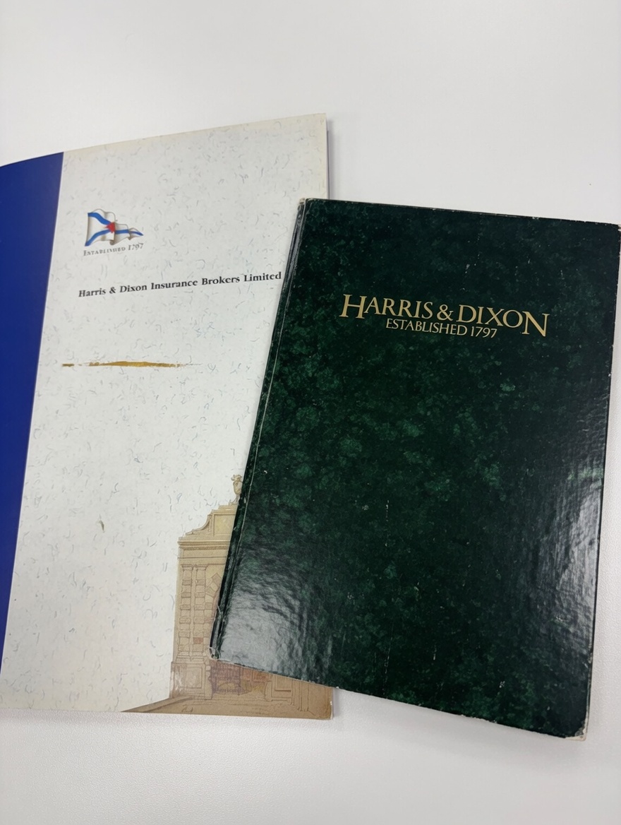 The green, gold-lettered Harris & Dixon book — Established 1797 — beside the blue Harris & Dixon Insurance Brokers brochure